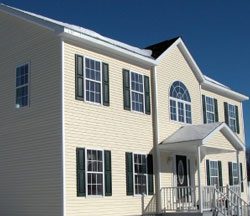 A house with cream-colored siding and black window shutters