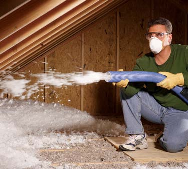 Man spraying insulation into attic space