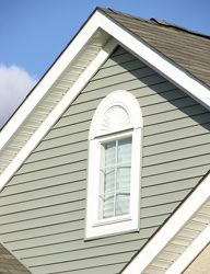 Exterior shot of a house with taupe siding and a white window