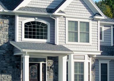 A gray home with white trim featuring beautiful windows and doors